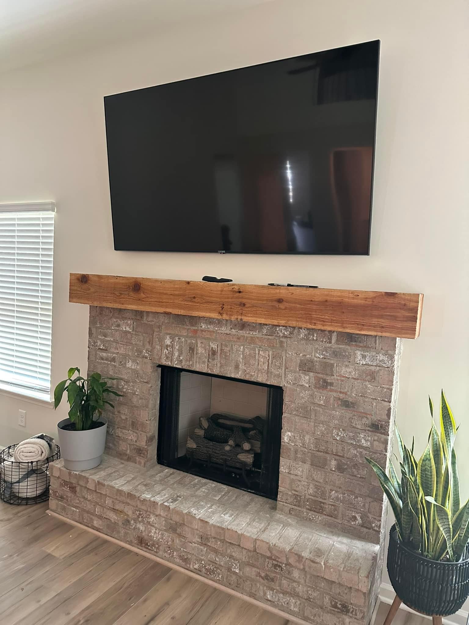 Same fireplace wall with a large flat-screen TV cleanly wall-mounted above the mantel after handyman service