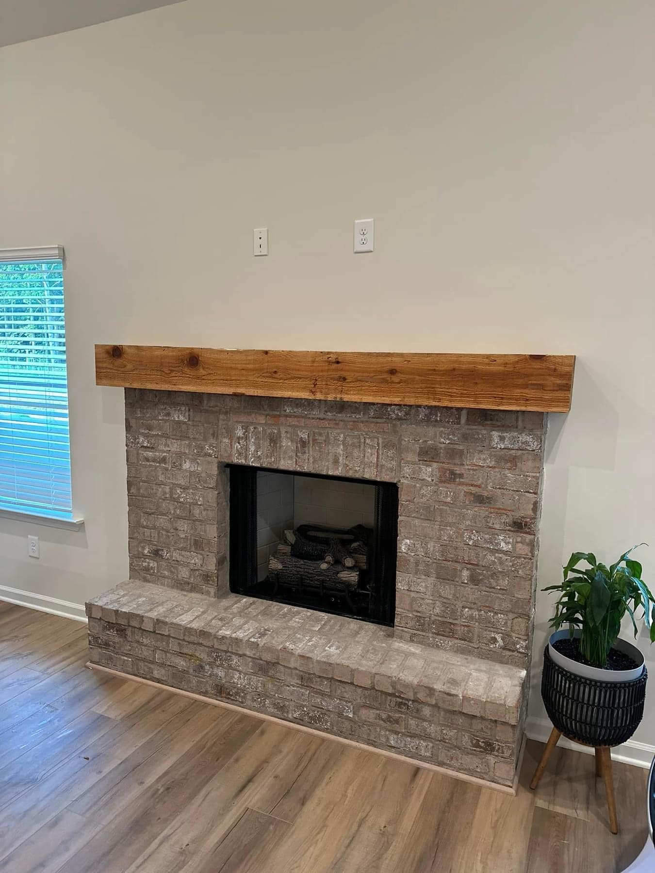 Living room fireplace wall with exposed electrical outlets above the mantel and no TV mounted before handyman service