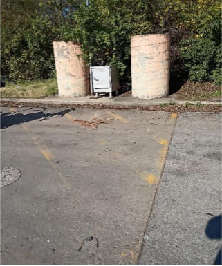 Faded, barely visible parking lot stripes next to weathered concrete bollards before restriping